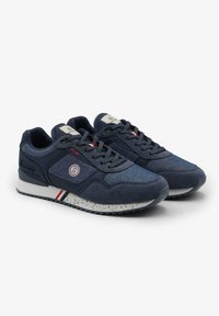 Navy blauwe sneakers van stof en suede, met een vetersluiting, een wit gespikkelde zool en een rond logo aan de zijkant.
