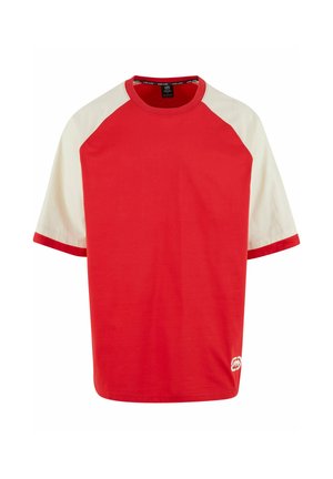T-shirt en coton rouge avec des manches raglan crème. Présente un col rond et un liseré contrasté aux manches. Détail du logo sur le côté inférieur.