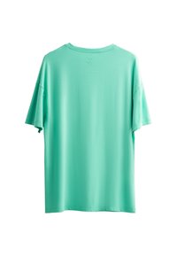 T-shirt mint vert à manches courtes avec une coupe relax, fabriqué en coton doux ; comporte un petit logo de ciseaux près de l'encolure.