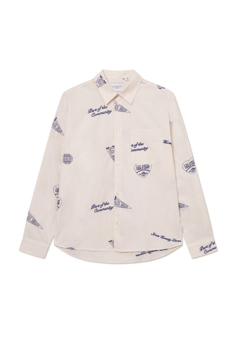 Light beige long-sleeve shirt with navy blue graphic designs and text. Features a button-down collar and a chest pocket. Cotton fabric.