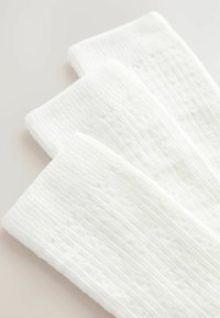 Tri páry bielych ponožiek vyrobených z mäkkého materiálu, s rebrovanou textúrou a jemným vzorom pre dodatočný detail.