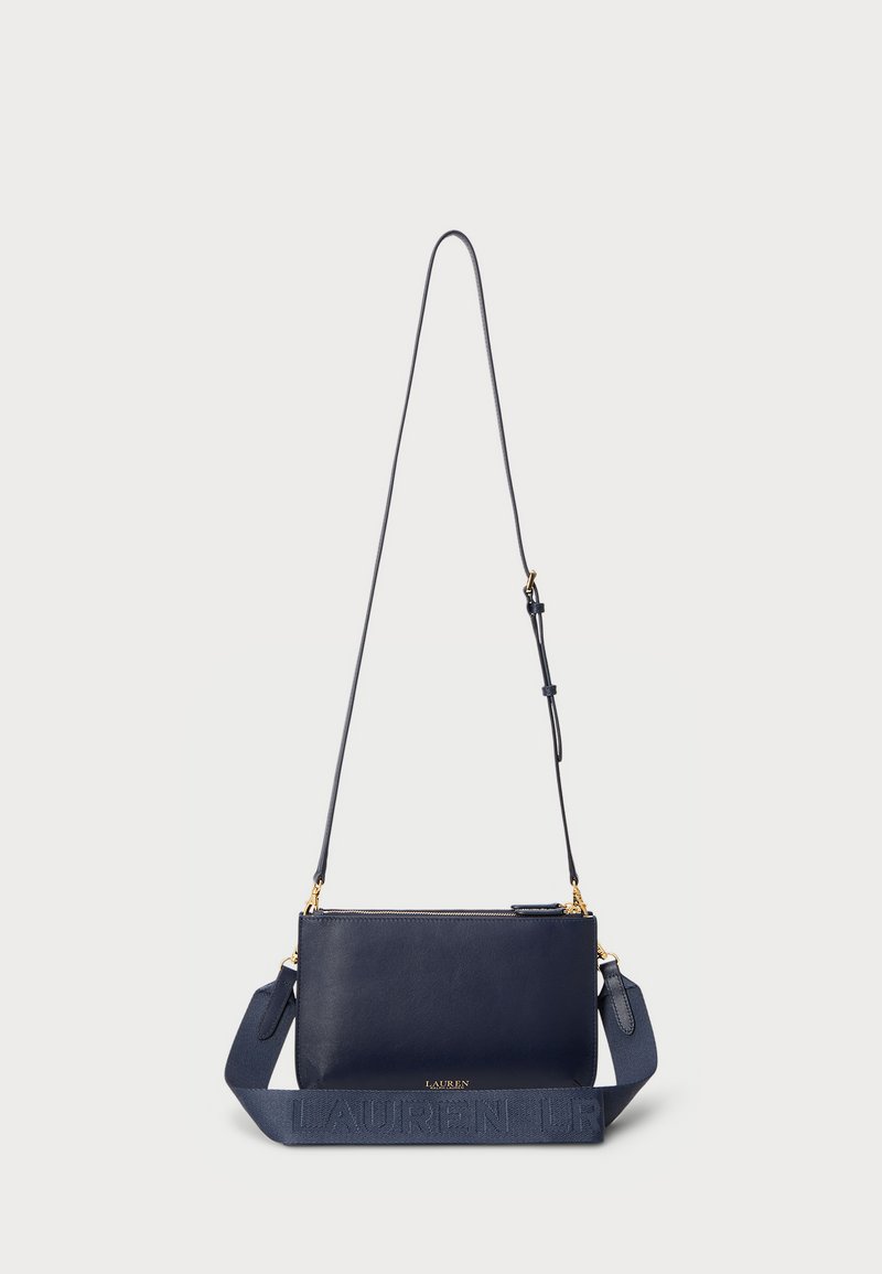 Bolsa de ombro em pele azul-marinho com uma alça texturizada, detalhes em dourado e fecho com zip. Apresenta um discreto logotipo na alça.