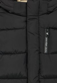 Černá péřová bunda s horizontálně prošitými panely, vysokým límcem a zapínáním na zip s visačkou s logem Calvin Klein Jeans.