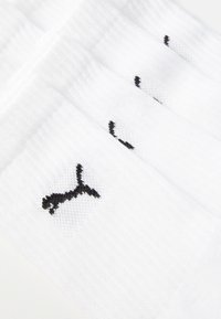 Hvide sokker med et ribbet design; har et sort broderet logo. Stoffet er blødt, struktureret og letvægtigt. Velegnet til afslappet brug.