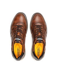 Zapatillas de cuero marrón con un acabado texturizado, acentos en negro y cordones marrones. Cuenta con una plantilla naranja y una suela blanca.