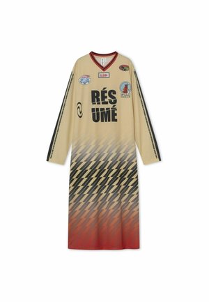 Šviesiai ruda ilgarankovė suknelė su raudonu V formos iškirpte, apačioje puošta juodo ir raudono gradientinio žąsies pėdų raštu bei įvairiaspalviais pleistrais.