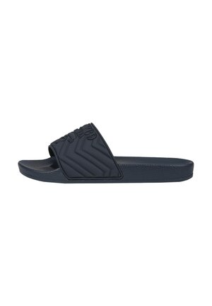 Schwarze Slide-Sandale mit strukturiertem Fußbett und Riemen mit Chevron-Muster, geprägt mit Totenkopf und „1989“-Design.