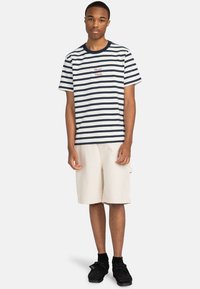 Camiseta a rayas en azul marino y blanco con el texto rojo "Por Favor Piensa" en el frente, combinada con pantalones cortos beiges y calzado negro.