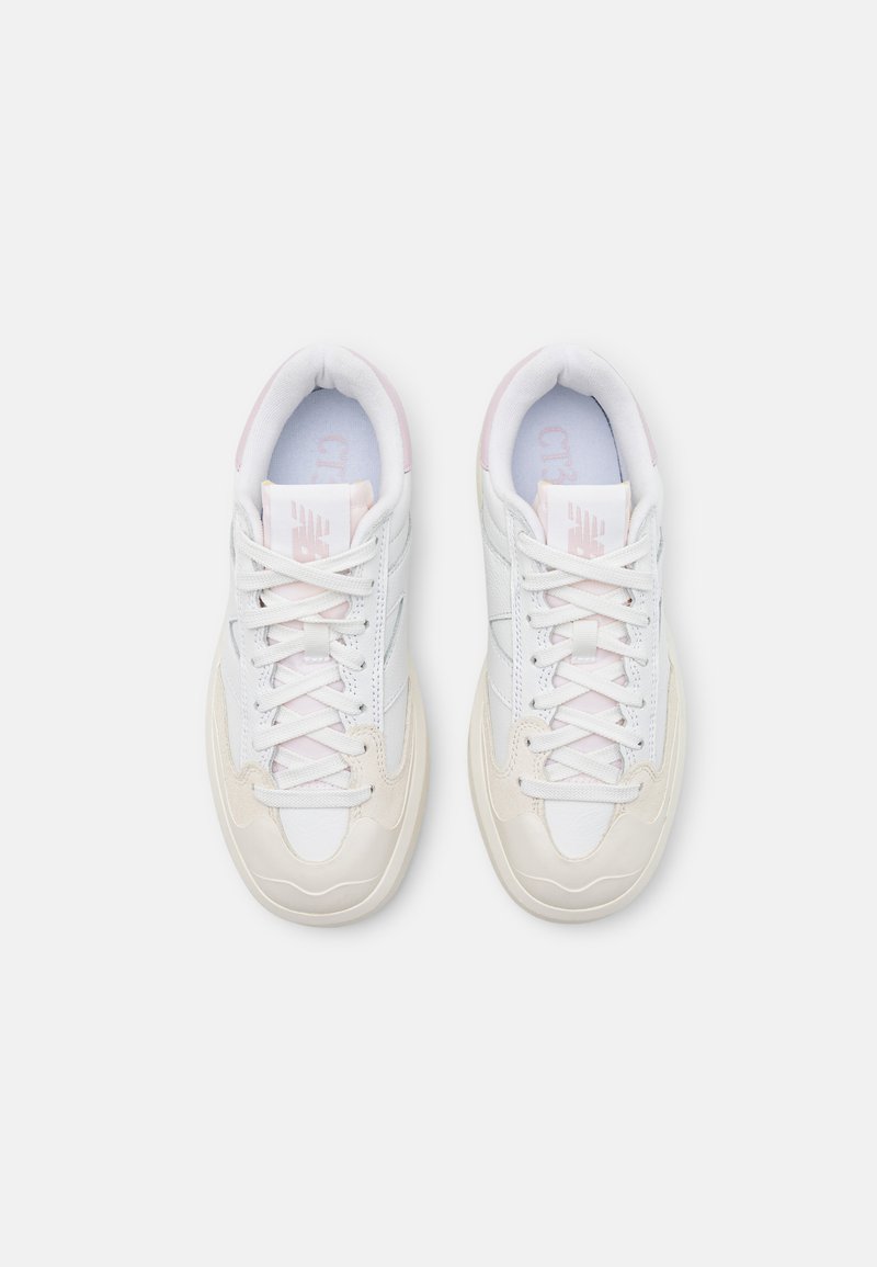 Baskets blanches avec des accents rose clair, présentant un dessus en cuir texturé et synthétique, un bout arrondi et un design classique à lacets.