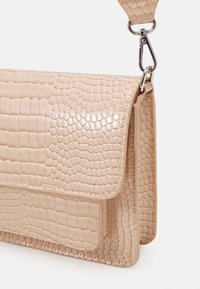 Borsa in ecopelle beige chiaro con motivo coccodrillo e finitura lucida, dotata di chiusura a pattina e tracolla removibile.