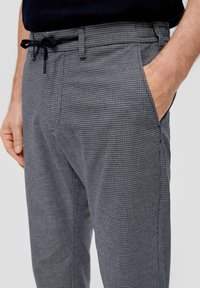 Pantalones de mezcla de algodón con un patrón de cuadros en gris oscuro y blanco, con cintura con cordón y bolsillos laterales.