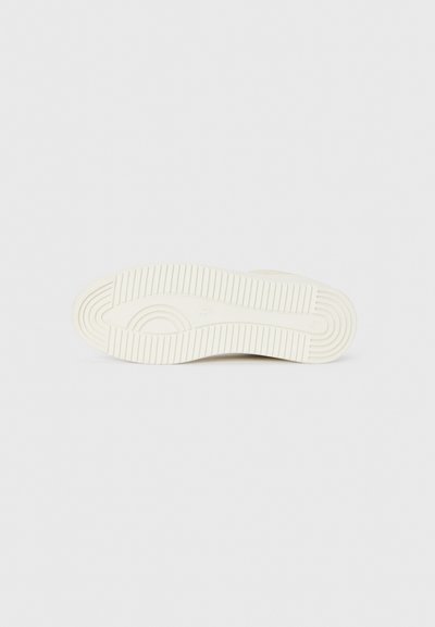Hvit sneaker-såle med et teksturert mønster som inkluderer horisontale og vertikale spor, med en rund form og minimalt design.