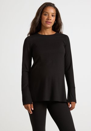 Svart, ribbad långärmad topp med avslappnad passform och rundad halsringning, tillsammans med matchande ribbade leggings. Mjukt, texturerat tyg.