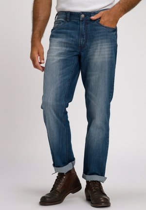 Donkerblauwe denim jeans met een rechte snit, lichte vervaging, opgerolde manchetten en een knoopsluiting, gecombineerd met bruine veterschoenen.