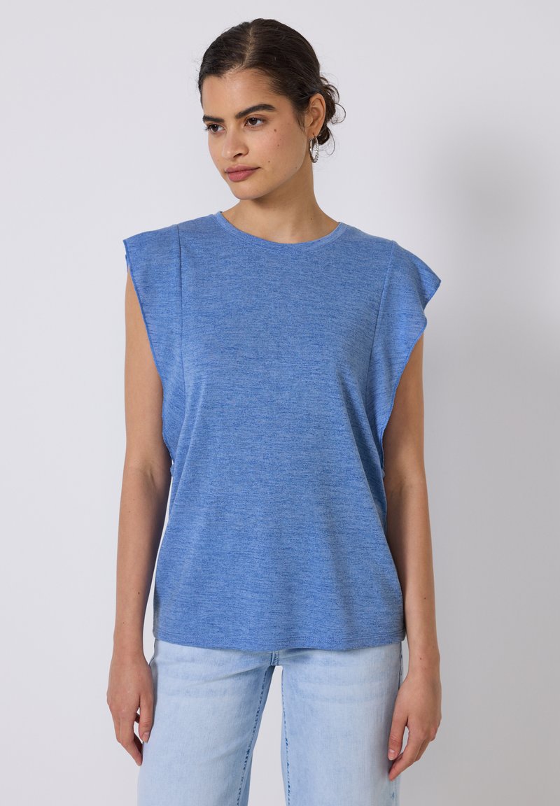 Top azul de manga corta hecho de tela texturizada. Presenta un escote redondo y un diseño de hombros estructurado, combinado con jeans de mezclilla claros.