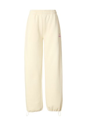 Pantalones deportivos color crema hechos de tela suave. Presentan una cintura elástica, puños con cordón y un pequeño logo rosa en el lateral.