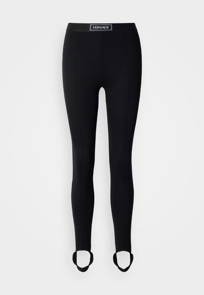 Leggings noirs à coupe ajustée, avec une taille haute ornée d'un logo. Comprend des boucles pour les pieds à la cheville pour un maintien sûr.