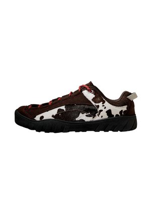Chaussure décontractée basse avec motif vache noir et blanc, détails en daim marron, lacets rouges et semelle épaisse en caoutchouc noir.