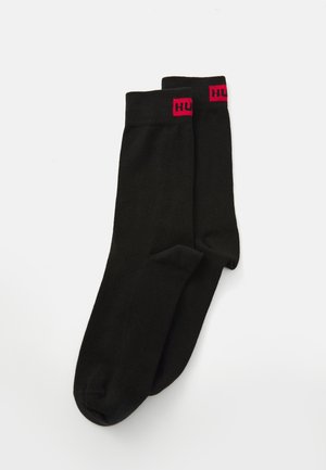Pair of black crew socks with red "HU" logo near the top cuff on a white background.