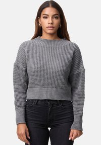 Grå kortad tröja med texturerad stickad design, bred ribbad halsringning och muddar. Nederst är den kombinerad med mörka jeans som ger en avspänd passform.