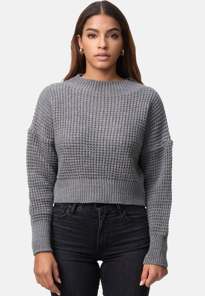 Grå kortad tröja med texturerad stickad design, bred ribbad halsringning och muddar. Nederst är den kombinerad med mörka jeans som ger en avspänd passform.
