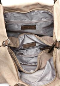 Tan fabric bag with beige leather accents. Interior features multiple compartments, including a zippered pocket and branded labels. Soft texture.