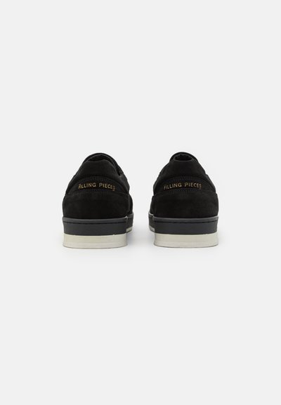 Black suede sneakers with white rubber soles. Includes embossed gold logo on the heel. Smooth texture and classic low-top design.