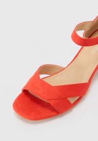 Oranges Wildledersandale mit einem Kreuzriemendesign und einer glatten Fußbett. Mit quadratischer Zehenpartie und einem schmalen Knöchelriemen für einen minimalistischen Look.