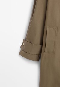 Brown cotton coat with buttoned cuffs and a single side pocket. The fabric has a smooth texture and a tailored design.