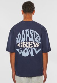 Mørkeblå bomulds crewneck t-shirt med stor, multifarvet tekst på ryggen, der står "DROPSIZE CREW LOVE" i forskellige skrifttyper.
