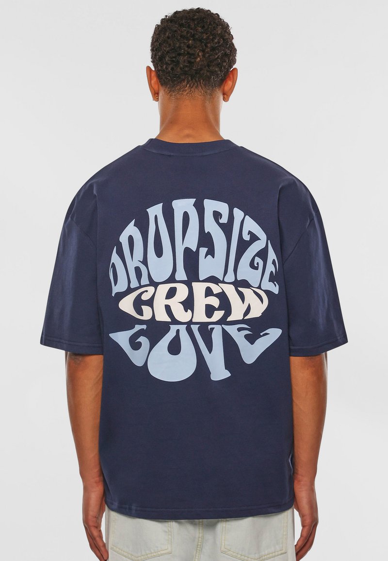 Mørkeblå bomulds crewneck t-shirt med stor, multifarvet tekst på ryggen, der står "DROPSIZE CREW LOVE" i forskellige skrifttyper.