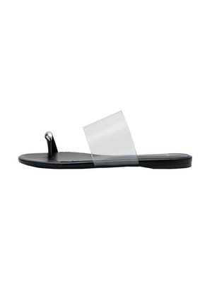 Sandalia plana negra con una tira ancha transparente y una lazo para el dedo con un detalle metálico plateado en la parte delantera.