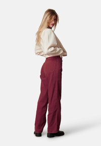 Bordeaux corduroy broek met een losse fit en zijzakken, gecombineerd met een crème-kleurige, oversized sweatshirt. Gladde textuur, ribstof.