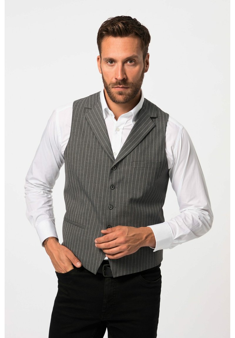 Gilet grigio a righe con una vestibilità aderente, cinque bottoni, rever a lancia e una tasca sul petto, indossato sopra una camicia bianca.