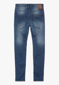 Modré denimové džíny mají úzký střih s vybledlým designem, pět kapes a hnědou koženou nášivku na zadním pasu.