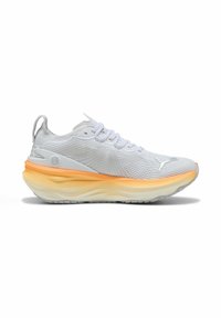 Scarpa atletica bianca con tomaia in mesh, intersuola arancione e crema, e suola testurizzata. Presenta un design con lacci e un tallone con linguetta.