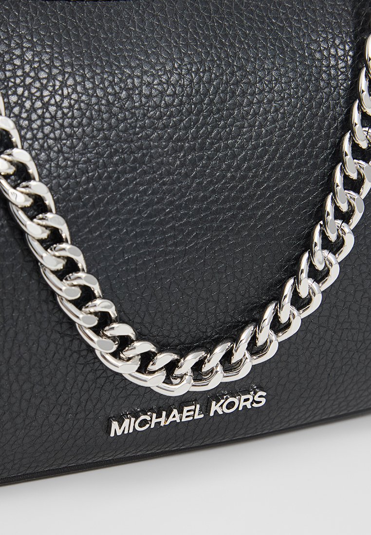 Borsa a tracolla in pelle nera con una maniglia a catena in argento. Presenta un logo argentato con la scritta "Michael Kors" sul davanti.