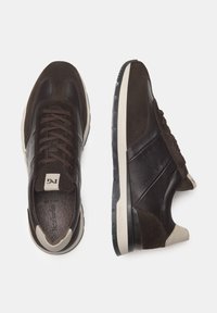 Sneakers in pelle e suede marrone con design a lacci, caratterizzati da un accento beige vicino al tallone e una suola in gomma testurizzata.