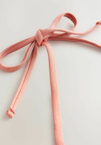 Rosa tygband med en slät textur, knutet i en rosett. Bandet har en subtil glans och två lösa ändar som hänger ner.