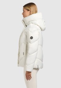 Biała pikowana kurtka z wyraźnym wzorem w kształcie jodełki, dużym kapturem i naszywką z logo Khujo. Gładki, błyszczący materiał z bocznymi kieszeniami.