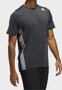 Tmavě šedé sportovní tričko s krátkým rukávem a třemi bílými pruhy po stranách, vyrobené z prodyšného materiálu, s kulatým výstřihem.