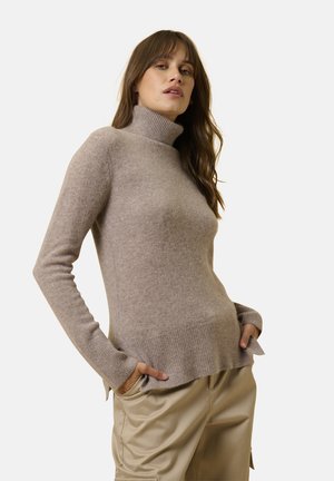 Maglione a collo alto color taupe chiaro realizzato in materiale morbido e strutturato, con maniche lunghe e orlo a coste con spacchi laterali.
