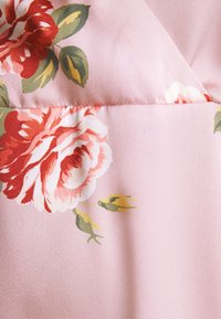 Tecido rosa com um grande padrão floral em vermelho e branco, apresentando folhas verdes e botões amarelos. Textura suave com um brilho sutil.