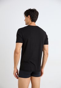 T-shirt noir à manches courtes en tissu doux, avec un col rond classique et une coupe décontractée, présenté de dos.