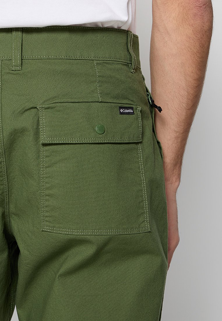 Grüne Cargo-Hosen mit einer Gesäßtasche, ausgestattet mit einem Druckverschluss und einem kleinen Columbia-Logo-Tag. Hergestellt aus strukturiertem Stoff mit einem strapazierfähigen Design.