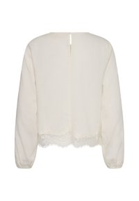 Blouse blanche à manches longues avec une petite fermeture à bouton au dos et un détail en dentelle sur l’ourlet du bas.