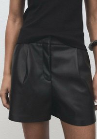 Black leather shorts with a smooth texture, featuring a pleated front, side pockets, and a tailored fit at mid-thigh length.