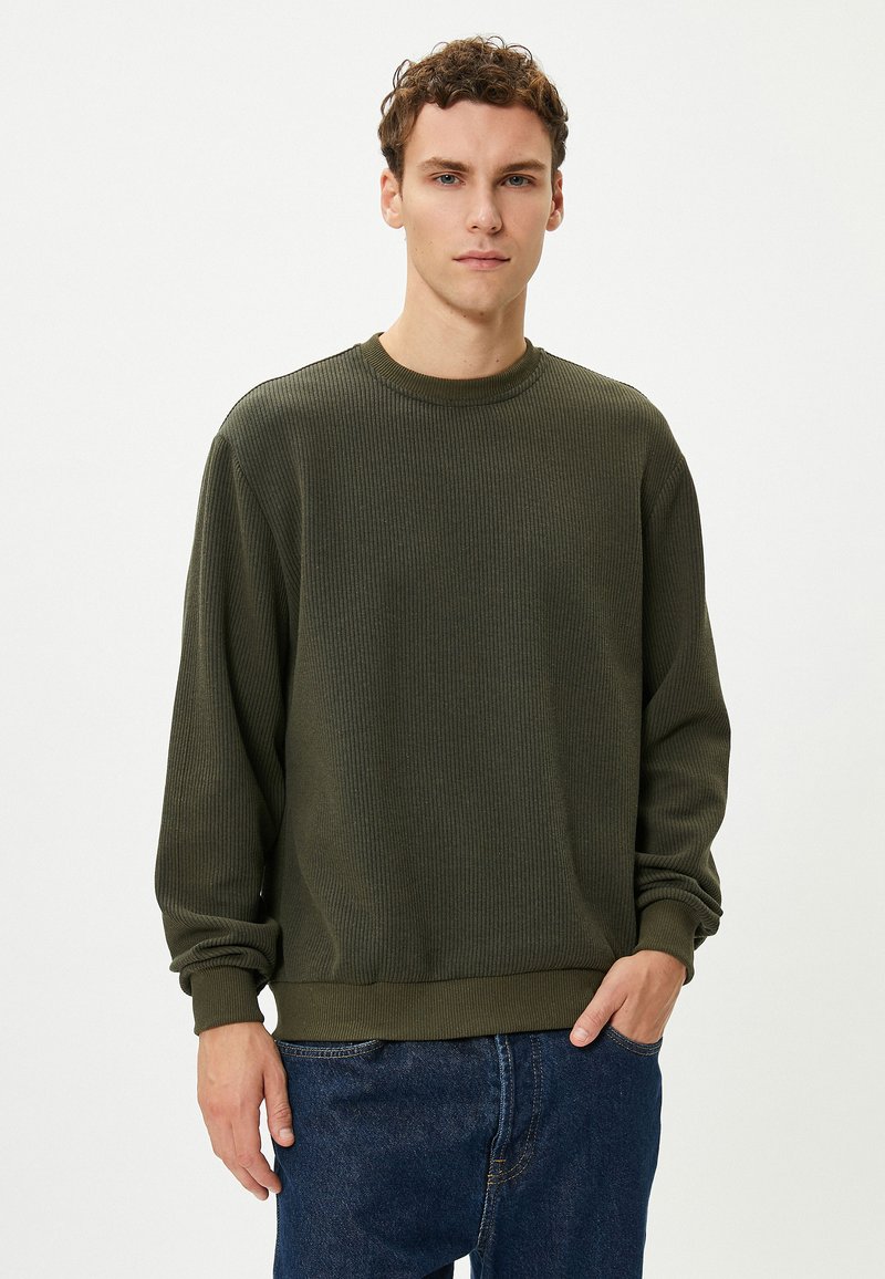 Donkergroene geribbelde sweatshirt met een ronde halslijn en lange mouwen. Gemaakt van katoen, heeft een ontspannen pasvorm en een zachte textuur.
