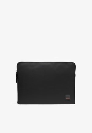 Sort rektangulær slank bærbar computersleeve med lynlås og lille kvadratisk logopatch i nederste højre hjørne.