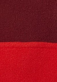 Roter und burgunderfarbener Fleece-Stoff mit einer weichen Textur. Das Material ist dicht und hat eine glatte Oberfläche, die horizontal in zwei Farbabschnitte unterteilt ist.
